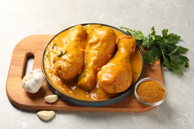 Photo of Tasty chicken curry and ingredients on grey textured table