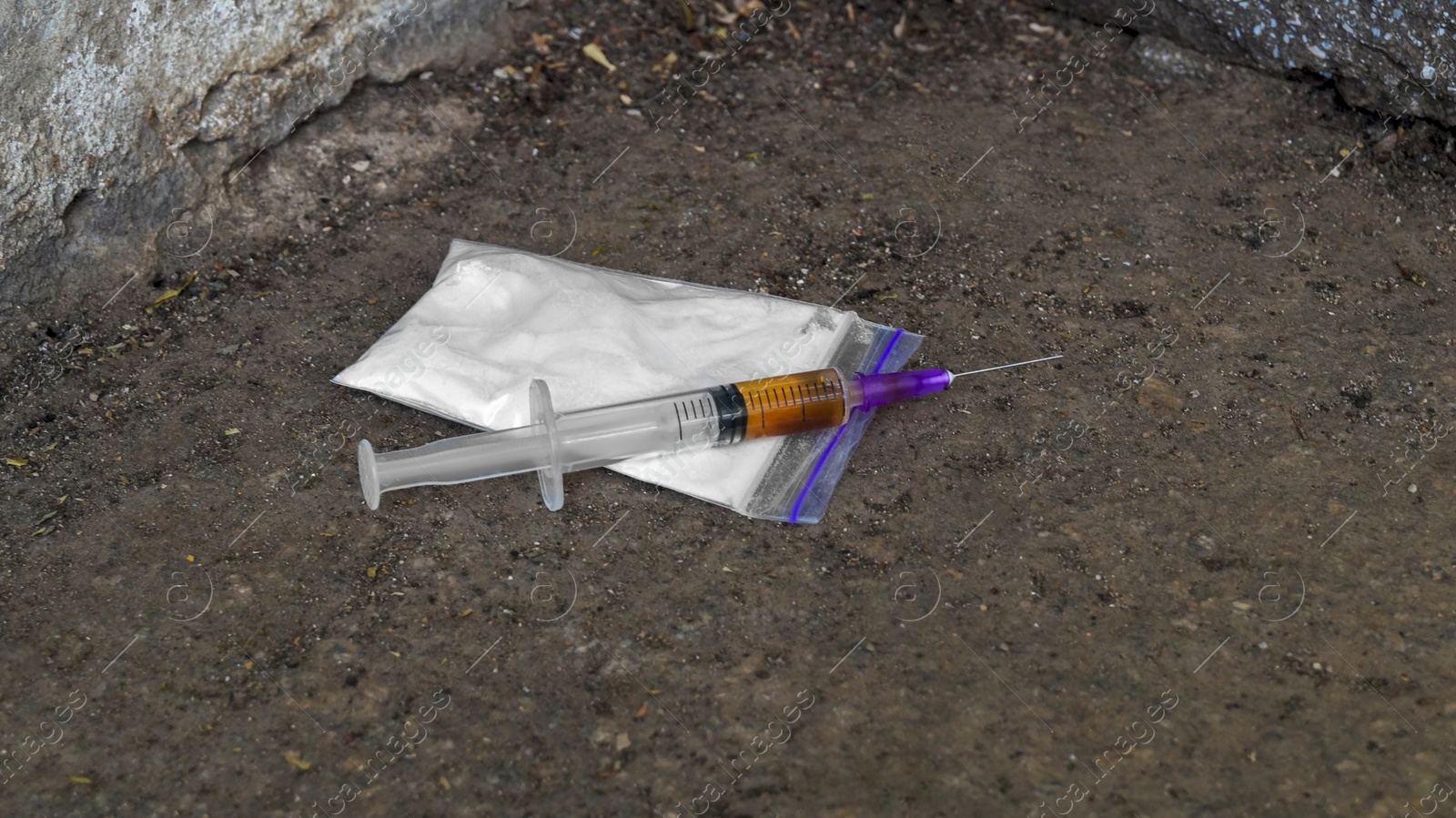 Photo of Plastic bag with powder and syringe on asphalt outdoors. Hard drugs
