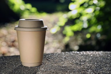 Photo of Cardboard takeaway coffee cup with lid on stone parapet outdoors, space for text