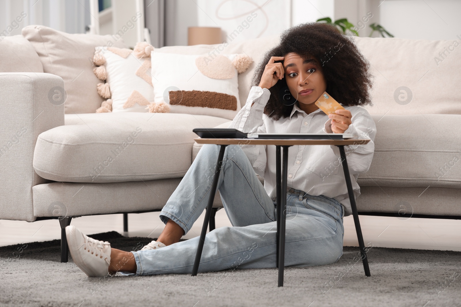 Photo of Shocked woman with calculator and credit card planning budget at home. Debt problem