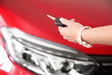 Woman with car key near new auto, closeup