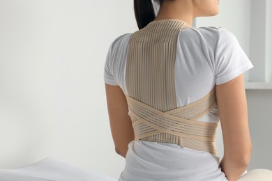 Photo of Closeup of woman with orthopedic corset indoors, back view. Space for text