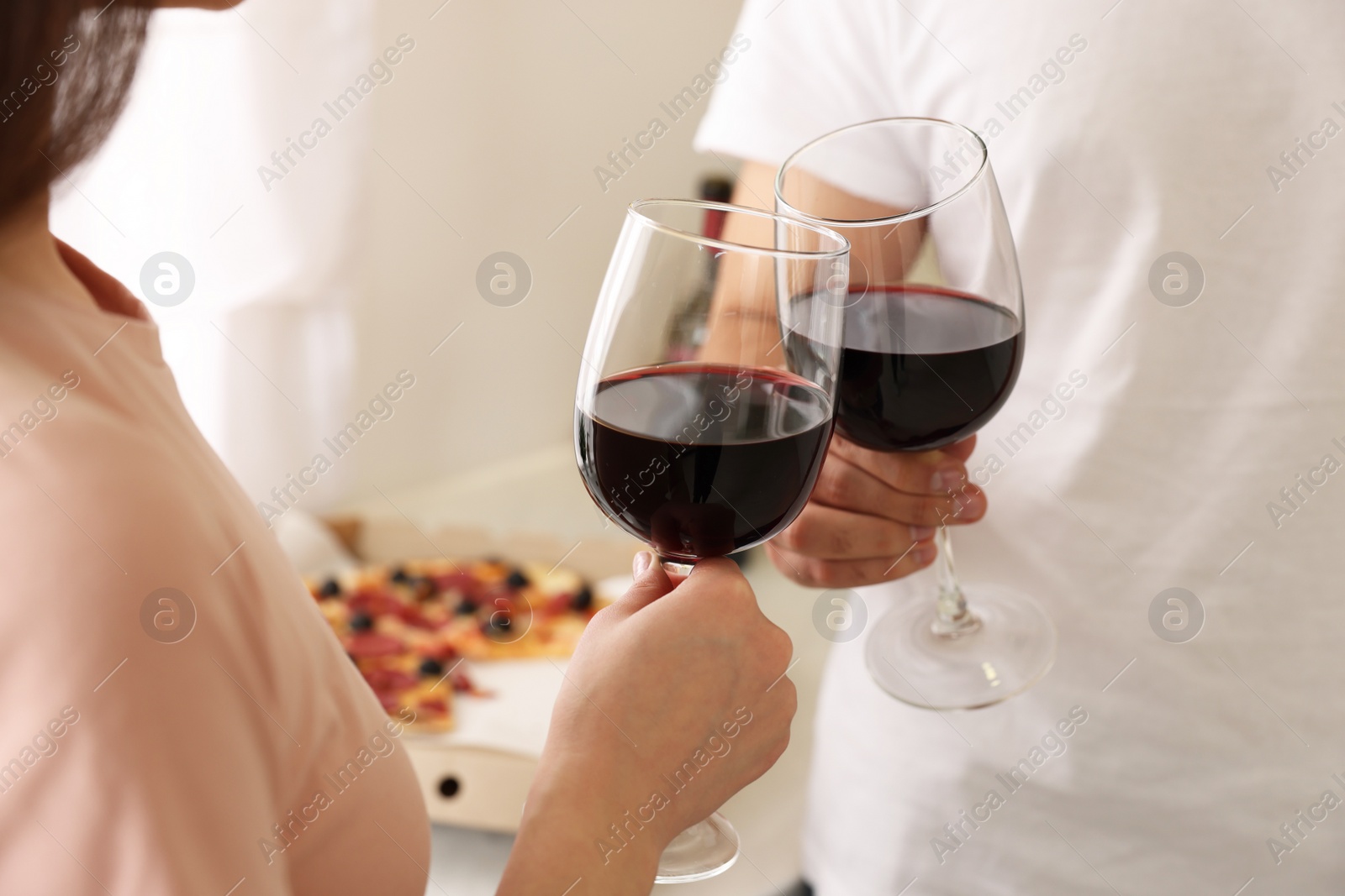 Photo of Couple clinking glasses of wine at home, closeup