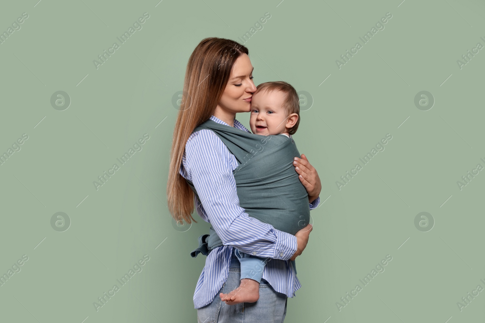 Photo of Mother holding her child in baby wrap on olive background