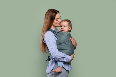 Photo of Mother holding her child in baby wrap on olive background