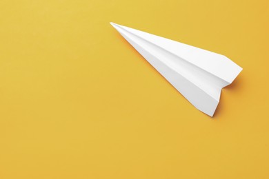 Photo of Handmade white paper plane on yellow background, top view. Space for text
