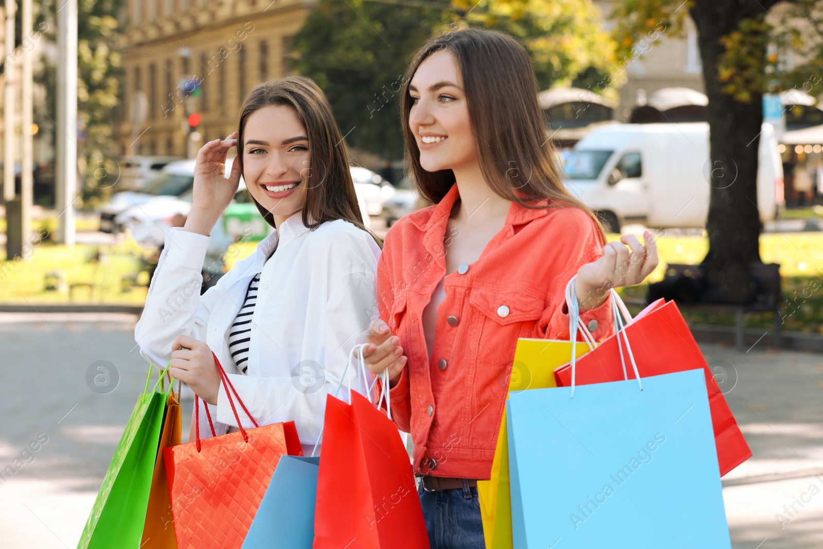 Photo of Beautiful young women with shopping bags on city street