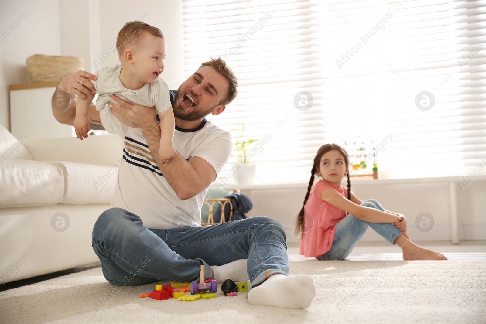 Photo of Unhappy little girl feeling jealous while father spending time with her baby brother at home