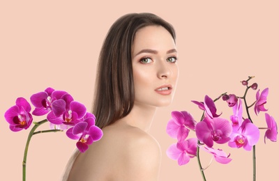 Image of Beautiful young woman and orchid flowers on light background. Spa portrait