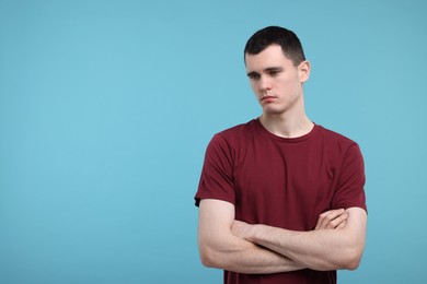 Portrait of sad man on light blue background, space for text