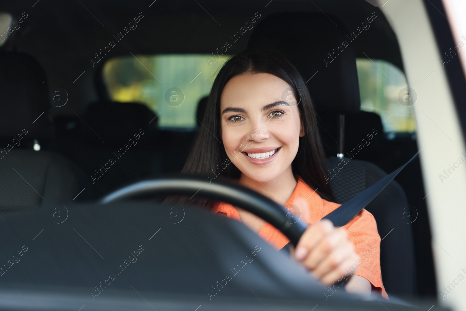 Photo of Enjoying trip. Happy young woman driving her car, view through windshield