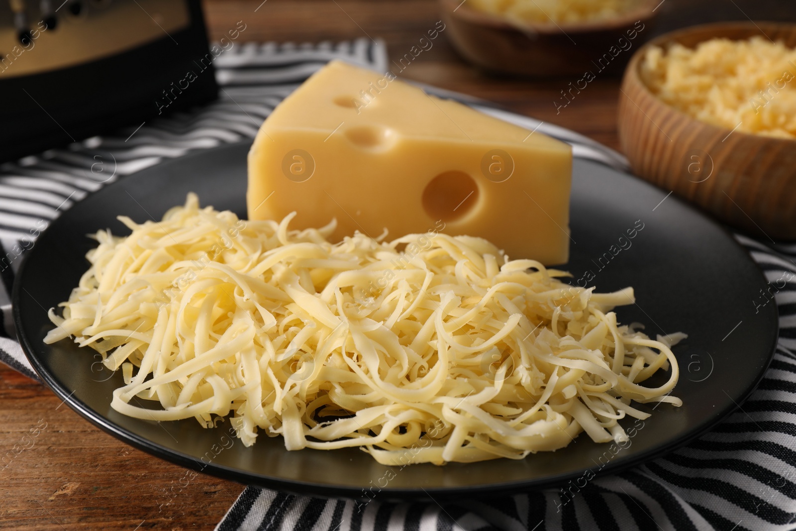 Photo of Grated and whole piece of cheese on wooden table, closeup