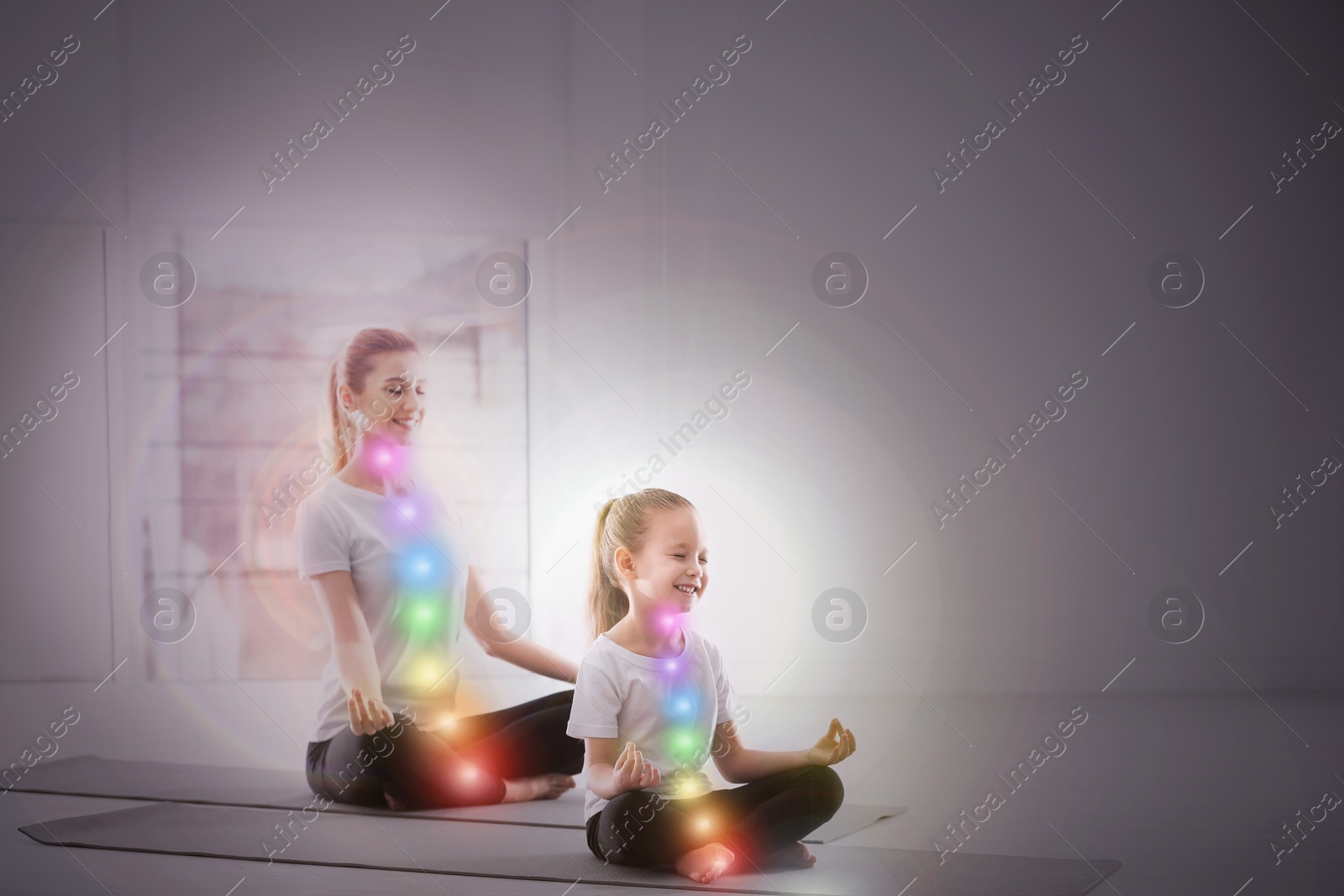 Image of Mother and daughter with chakra points practicing yoga in studio. Healing energy 