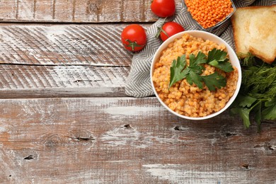 Photo of Delicious red lentils with parsley, tomatoes and bread on wooden table, flat lay. Space for text