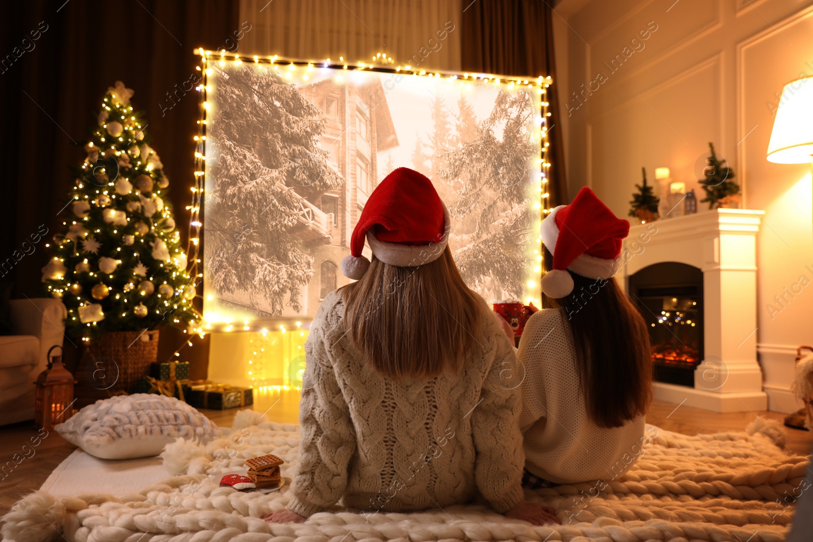 Image of Women watching Christmas movie via video projector in room. Cozy winter holidays atmosphere