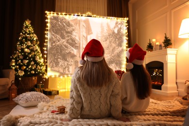 Women watching Christmas movie via video projector in room. Cozy winter holidays atmosphere