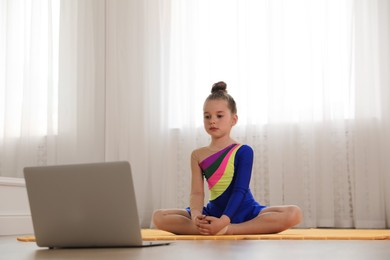 Cute little girl watching online dance class indoors
