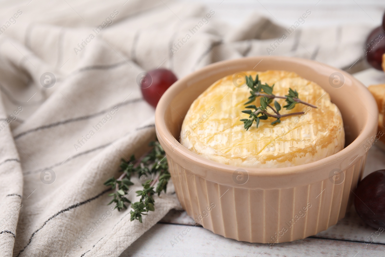 Photo of Tasty baked camembert and thyme in bowl on table, closeup