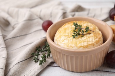 Photo of Tasty baked camembert and thyme in bowl on table, closeup