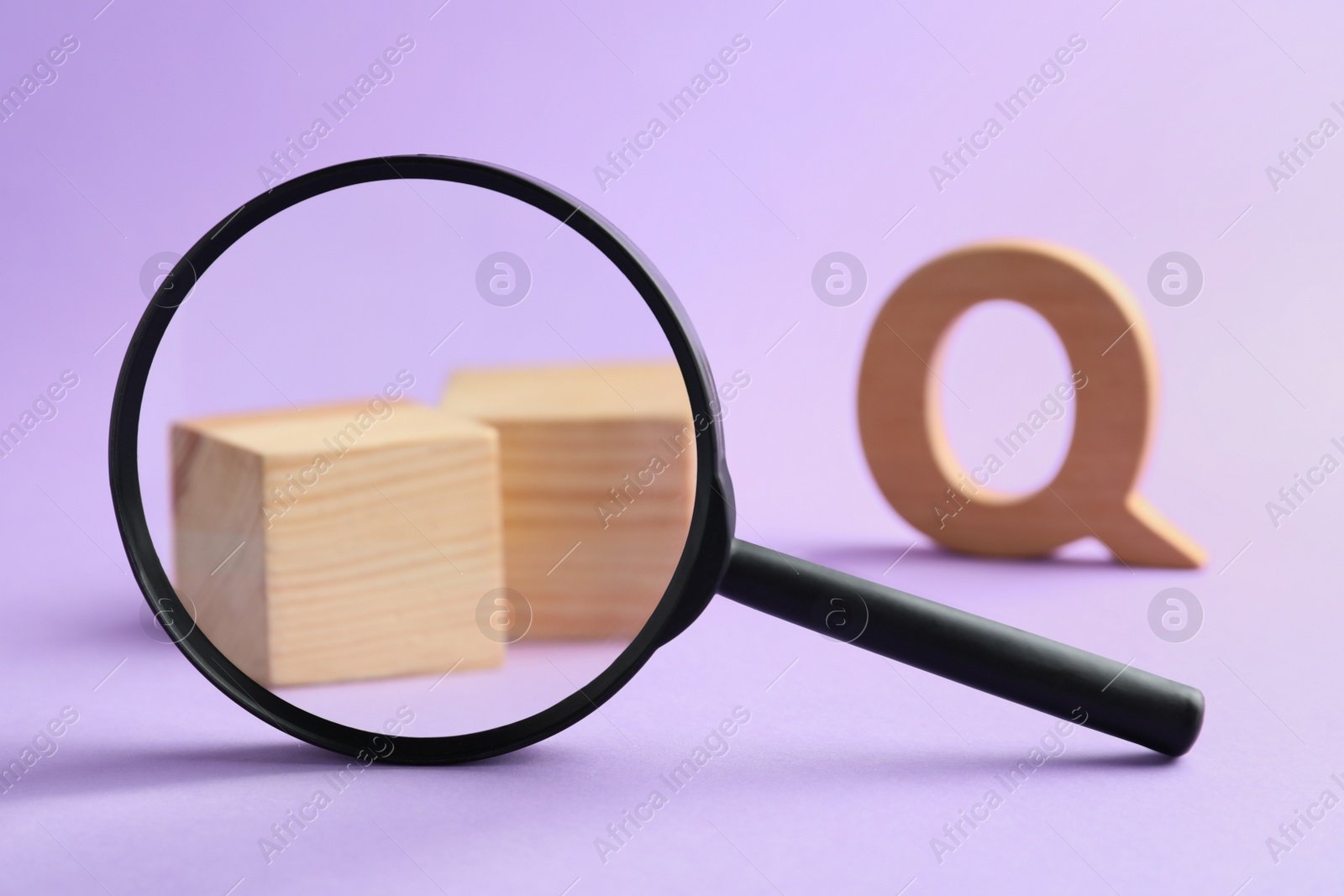 Photo of Magnifier glass, wooden cubes and letter Q on violet background, closeup. Find keywords concept