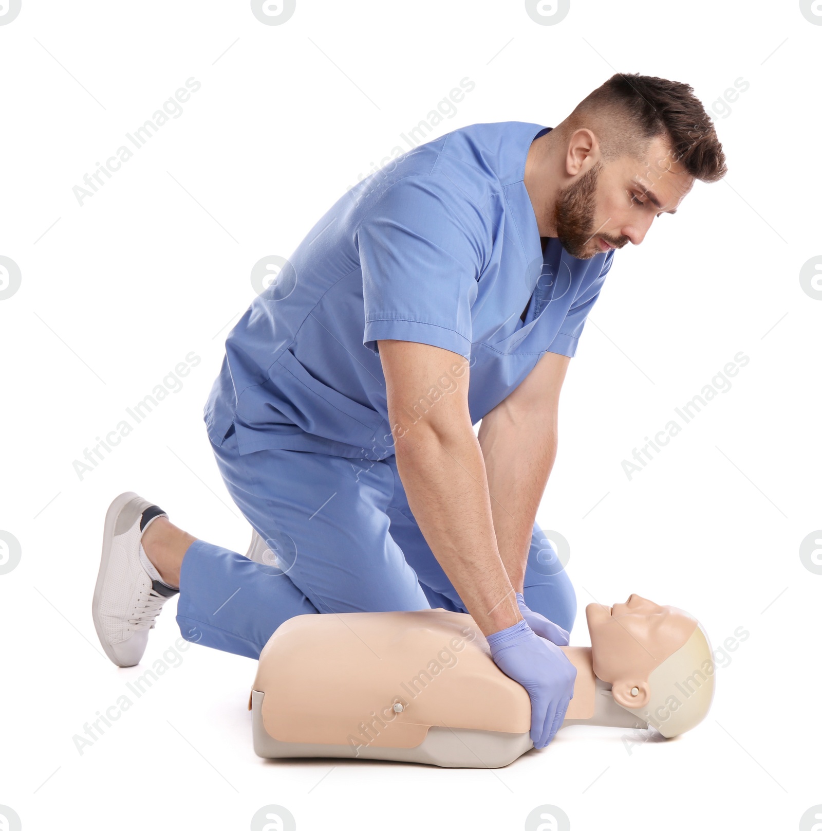 Photo of Doctor in uniform practicing first aid on mannequin against white background