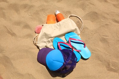 Photo of Sunscreens, seashell and beach accessories on sand, flat lay