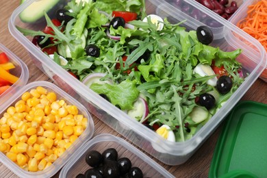 Photo of Set of plastic containers with fresh food on wooden  table