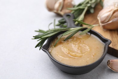 Delicious turkey gravy, rosemary and garlic on light grey table, closeup. Space for text