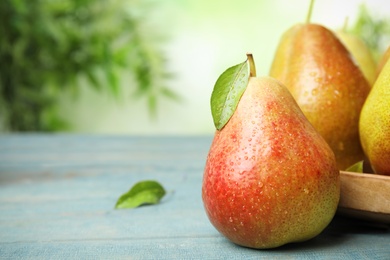 Ripe juicy pears on blue wooden table against blurred background, closeup. Space for text