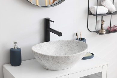 Different bath accessories and personal care products near sink on bathroom vanity