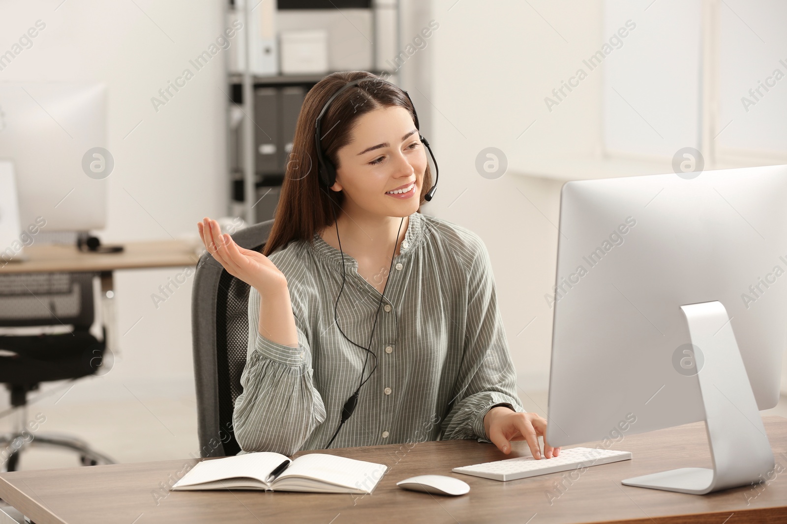 Photo of Hotline operator with headset working on computer in office