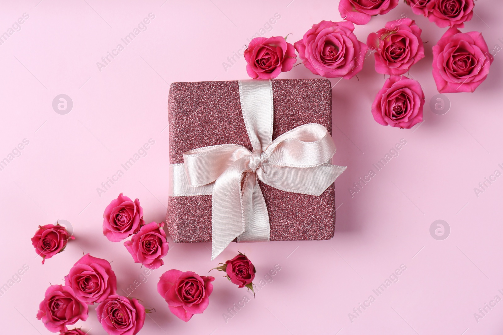 Photo of Beautiful roses and gift box on color background, top view