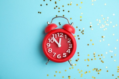 Flat lay composition with alarm clock and confetti on color background. Christmas countdown