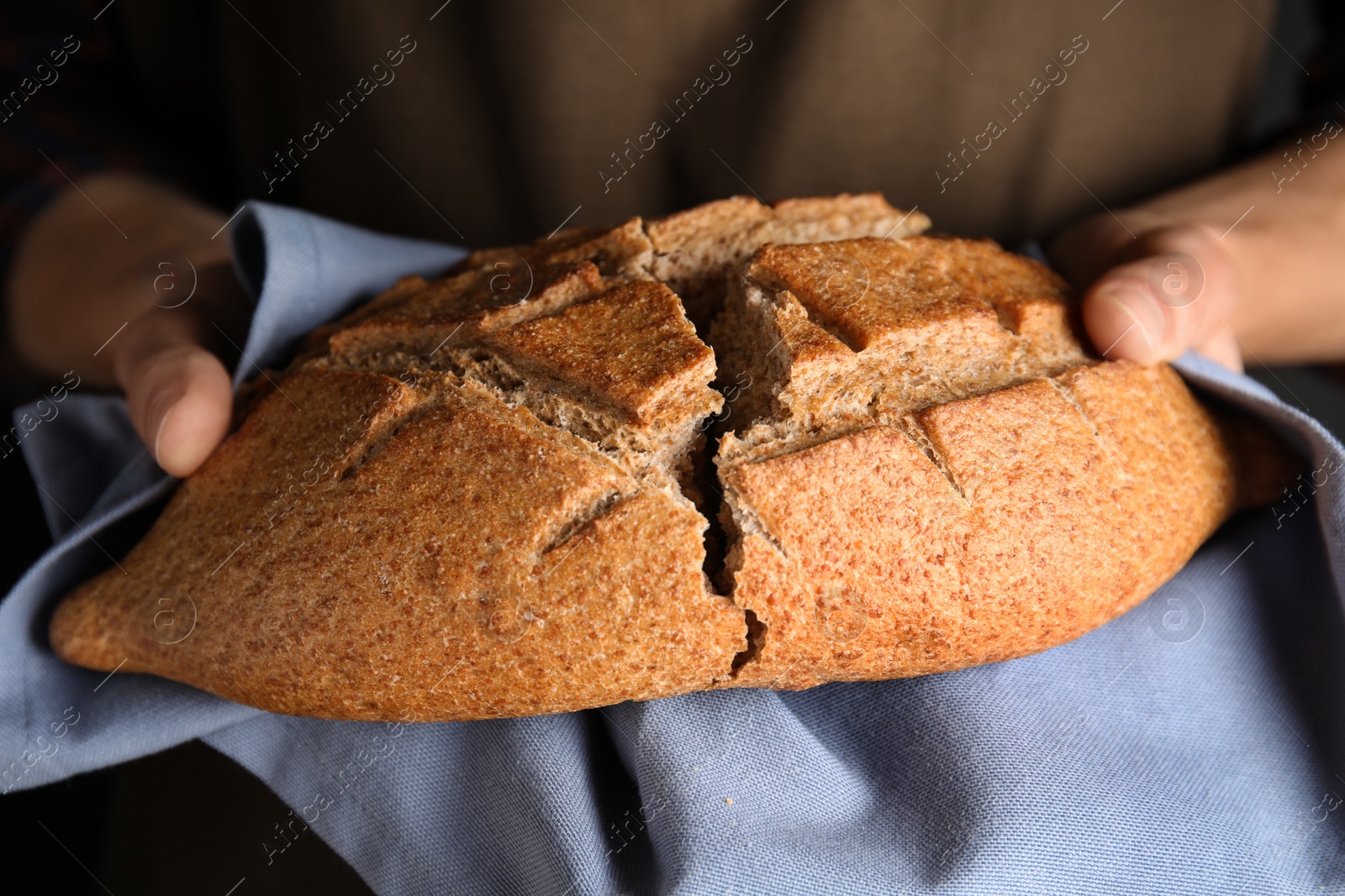 Photo of Man holding loaf of bread, closeup view