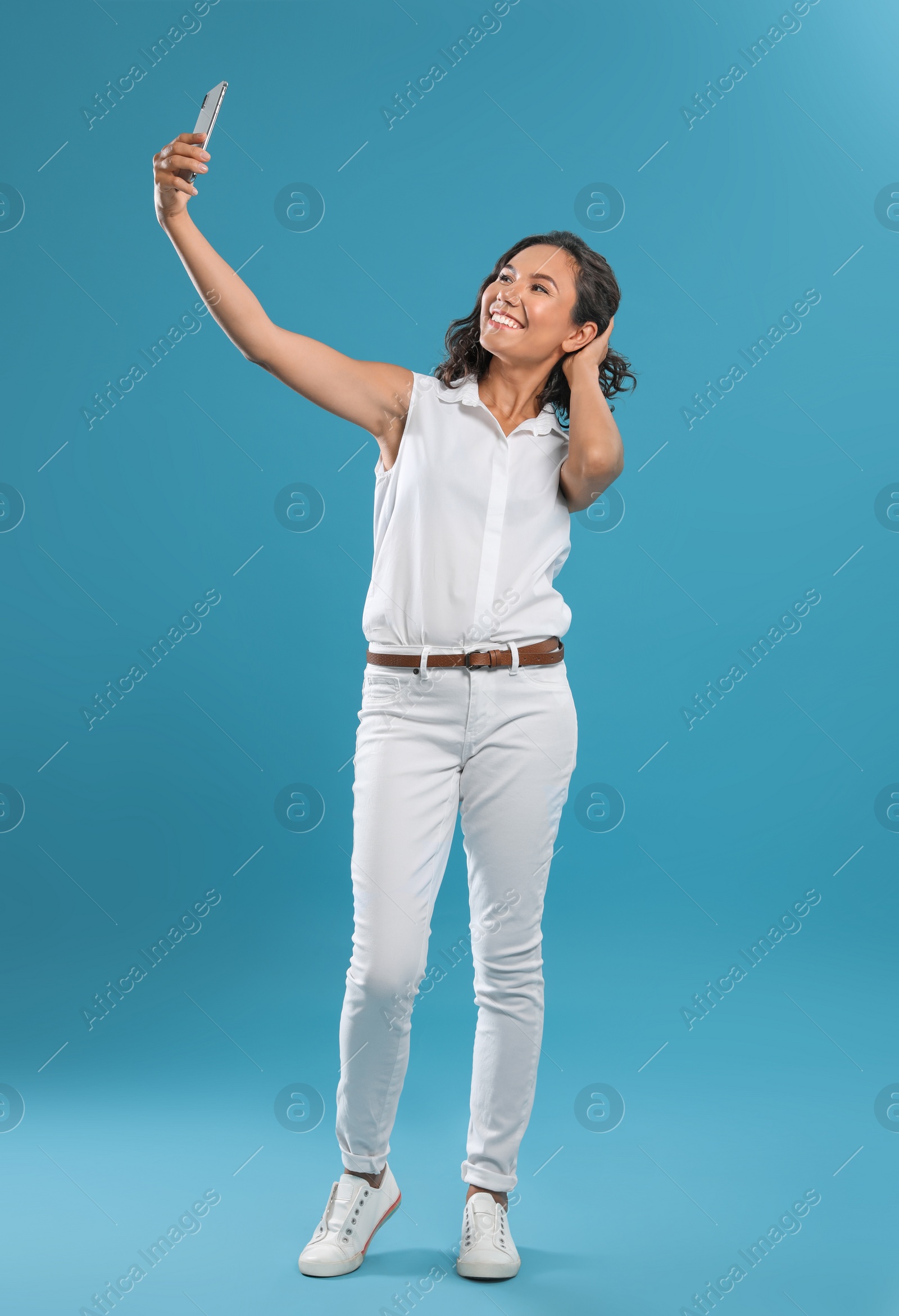 Photo of Happy young woman taking selfie on blue background