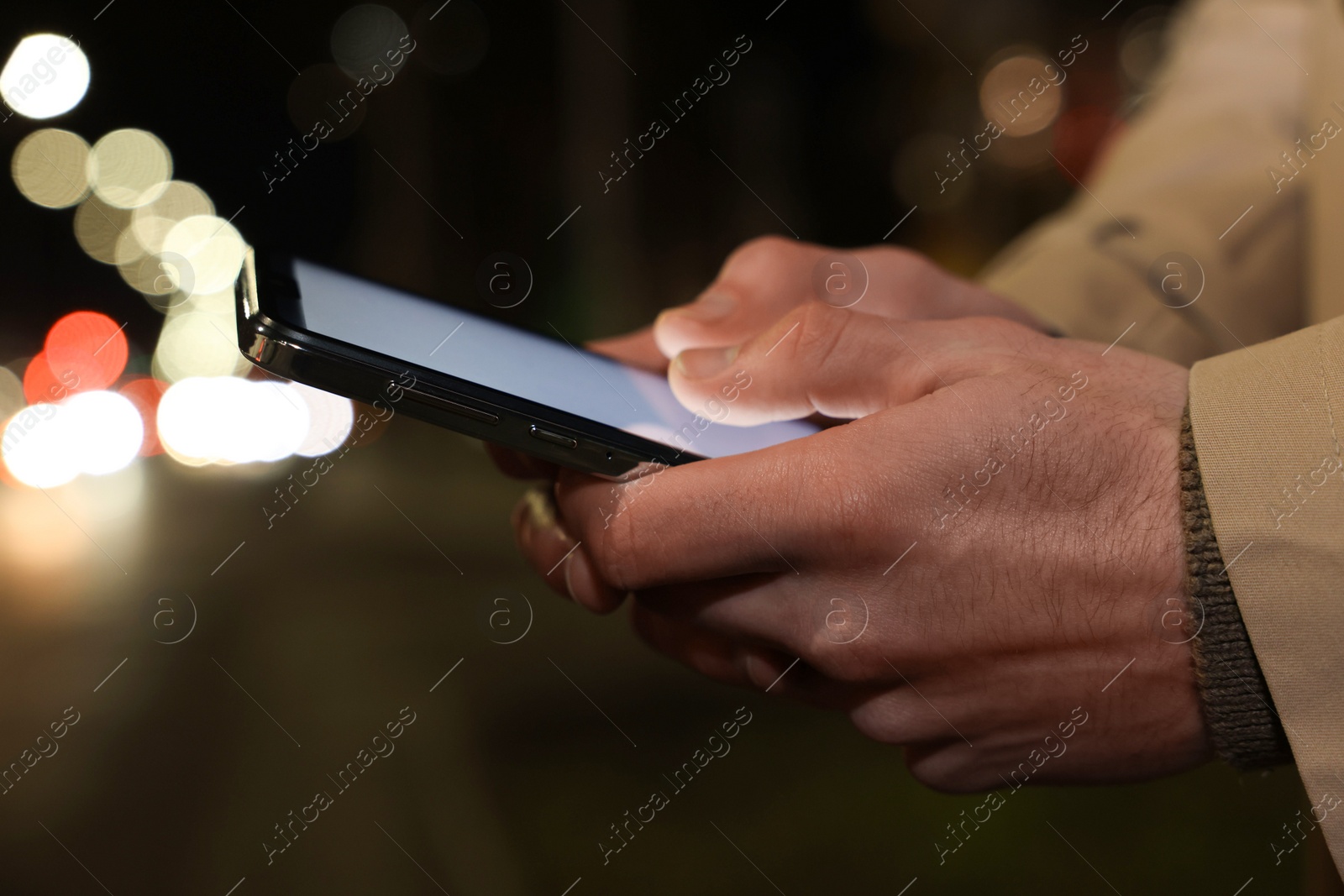 Photo of Man using smartphone on night city street, closeup