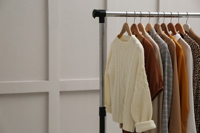 Rack with different stylish clothes near grey wall. Space for text