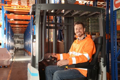 Photo of Happy worker sitting in forklift truck at warehouse