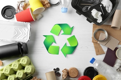 Photo of Recycling symbol and different garbage on wooden background, top view