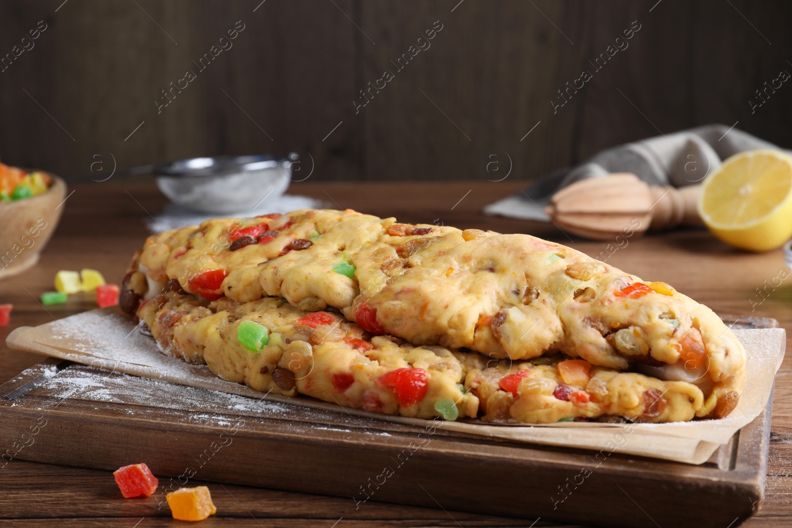 Photo of Unbaked Stollen with candied fruits and raisins on wooden table, closeup