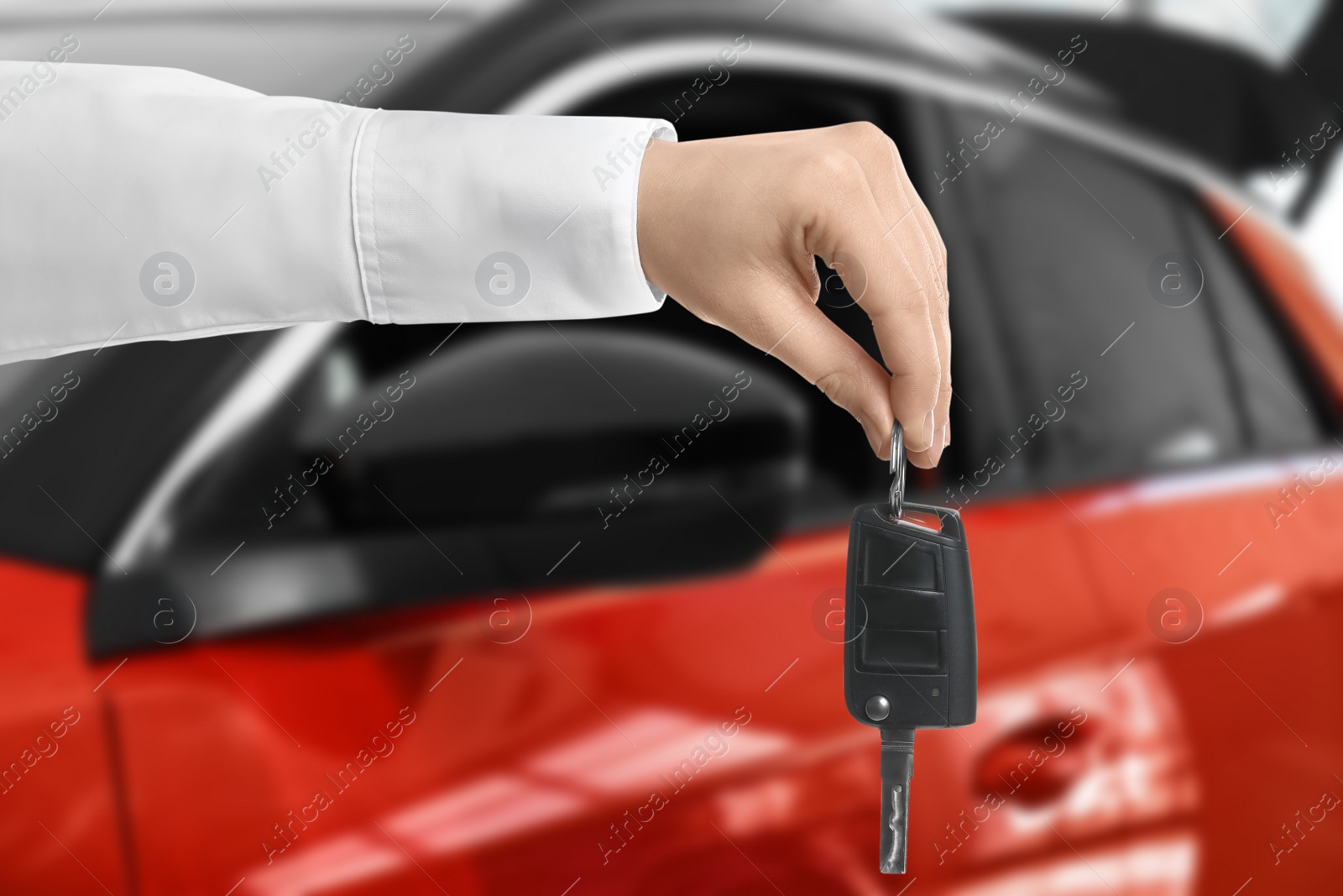 Image of Car buying. Man holding key against blurred automobile, closeup