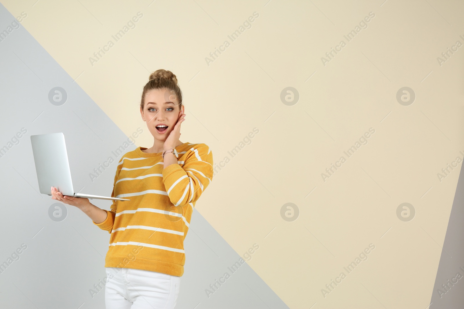 Photo of Portrait of emotional young woman with laptop on color background. Space for text