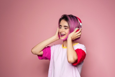Photo of Young woman with trendy hairstyle listening to music against color background