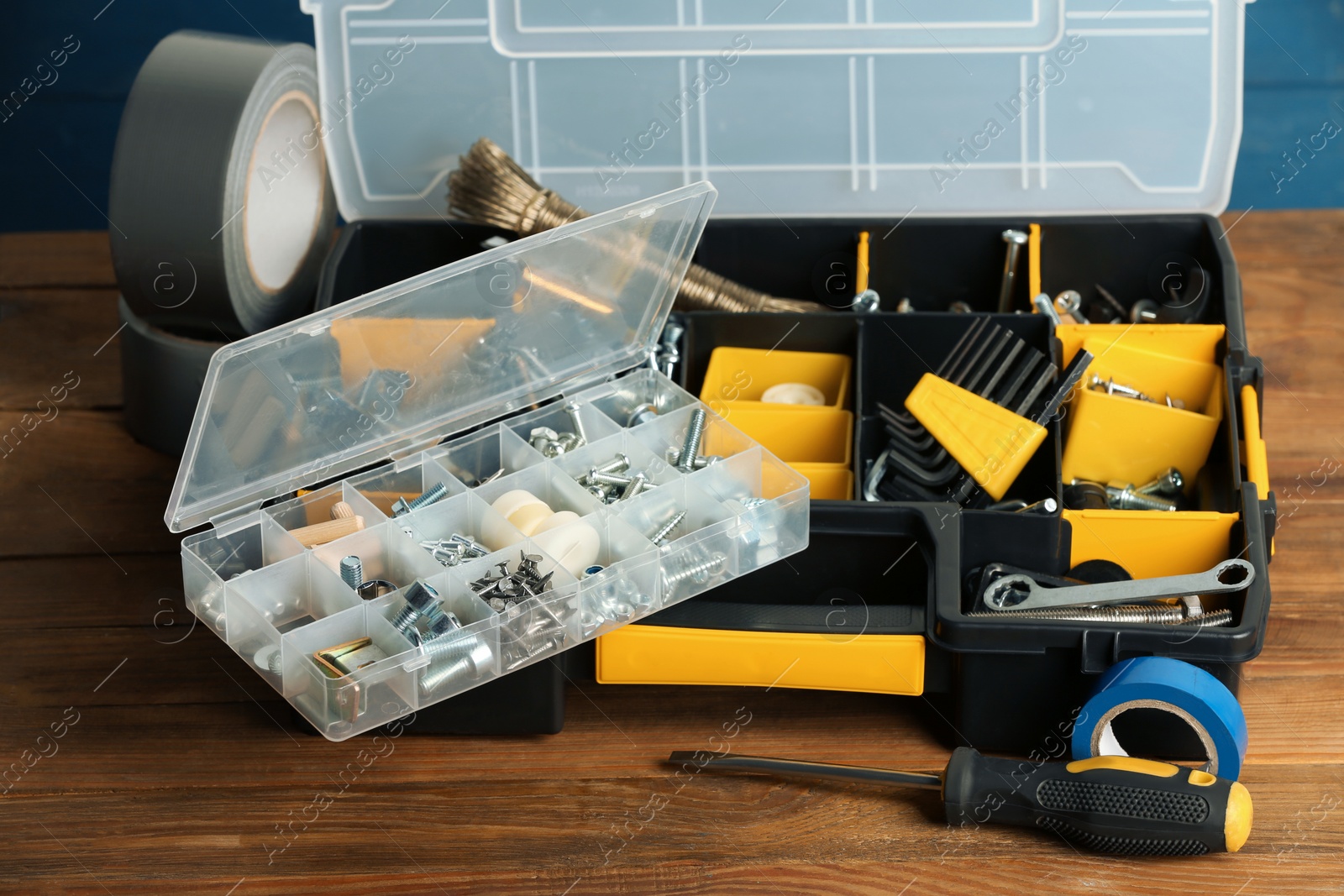 Photo of Plastic boxes with different furniture fittings and tools on wooden table