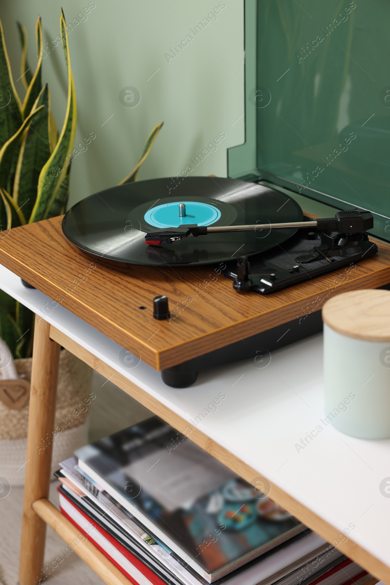 Photo of Stylish turntable with vinyl record on console table in room