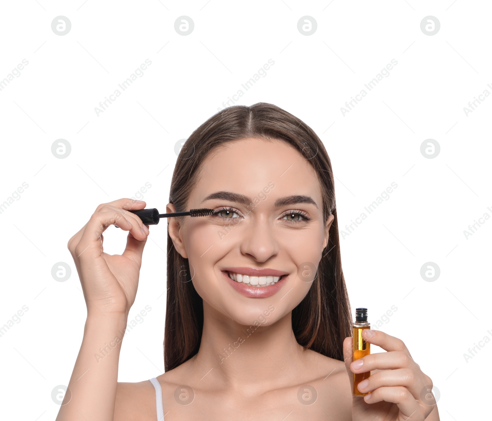 Photo of Young woman applying oil onto her eyelashes on white background