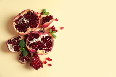 Ripe pomegranates and seeds on color background, top view with space for text