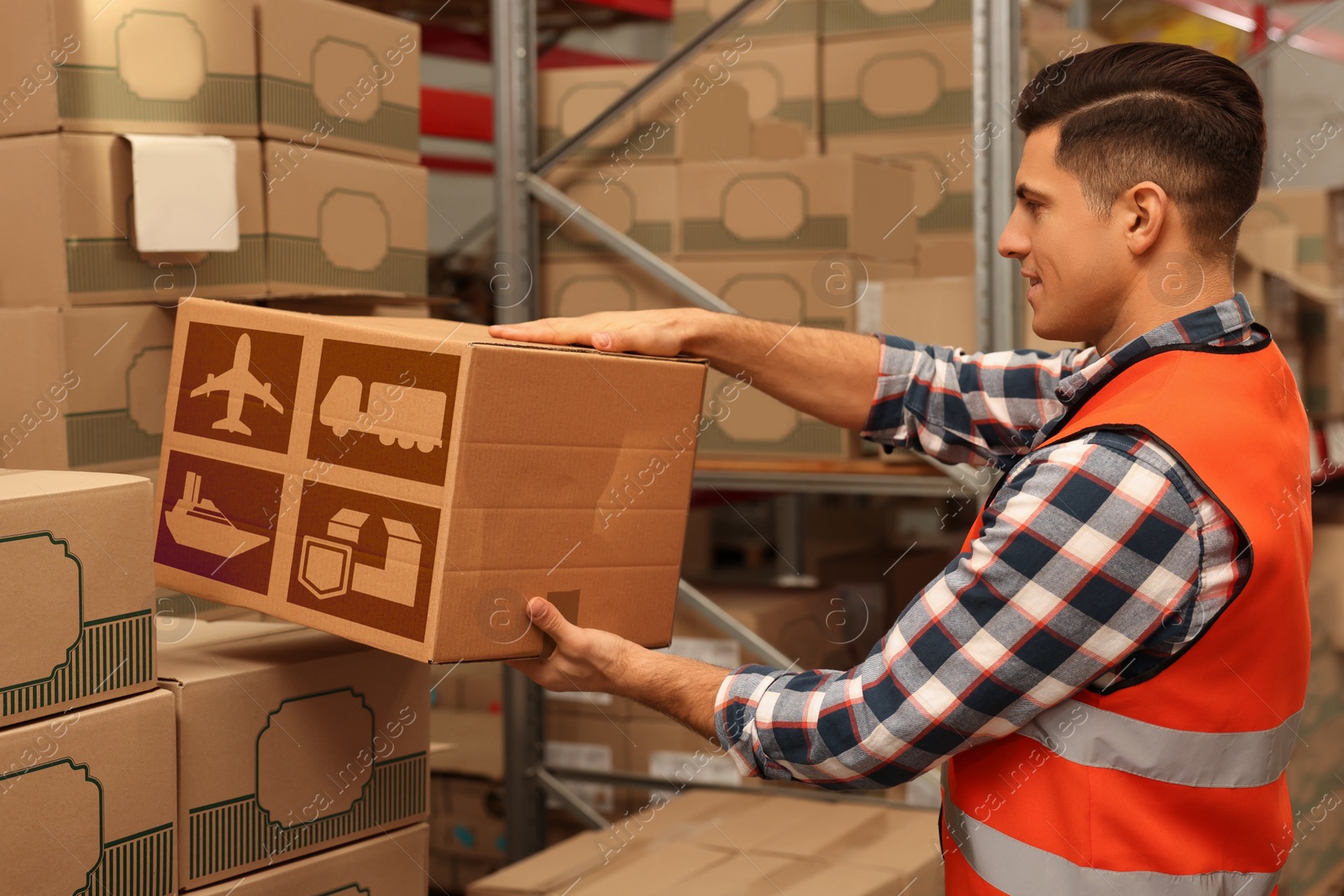 Image of Worker stacking cardboard boxes with shipping icons in warehouse. Wholesaling