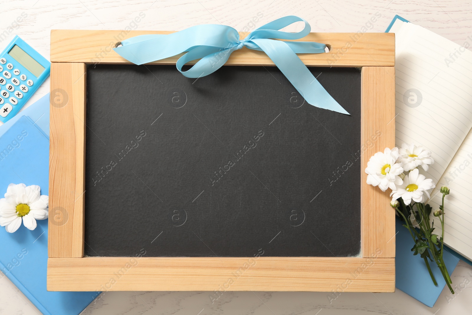 Photo of Blackboard, stationery and flowers on white wooden table, flat lay with space for text. Teacher's Day