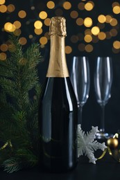 Happy New Year! Bottle of sparkling wine, glasses and festive decor on black background